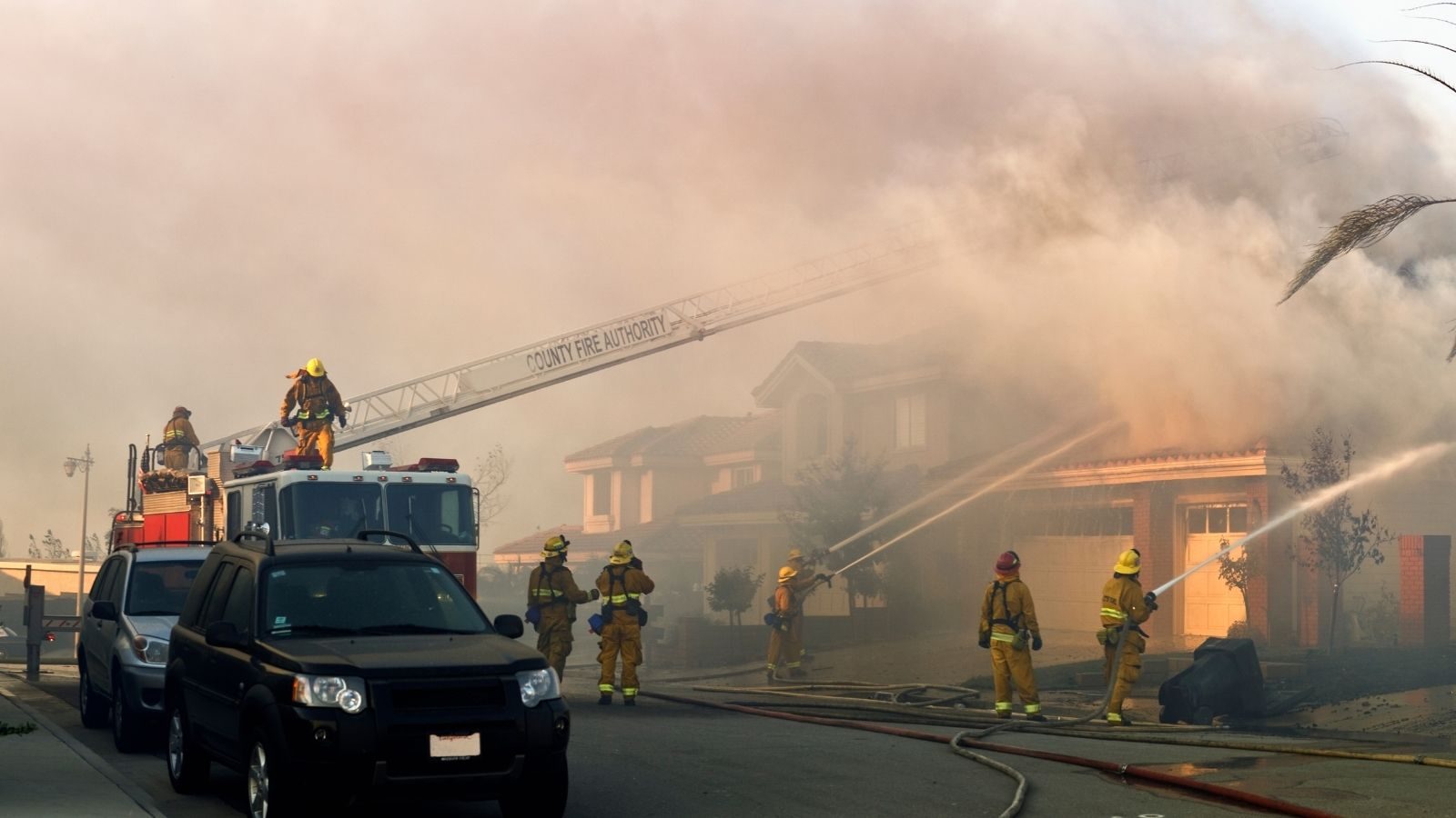 Fire fighters putting out house fire in a suburban neighborhood