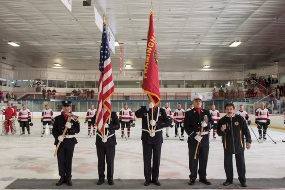 Firefighters holding flags at the start of a hockey game